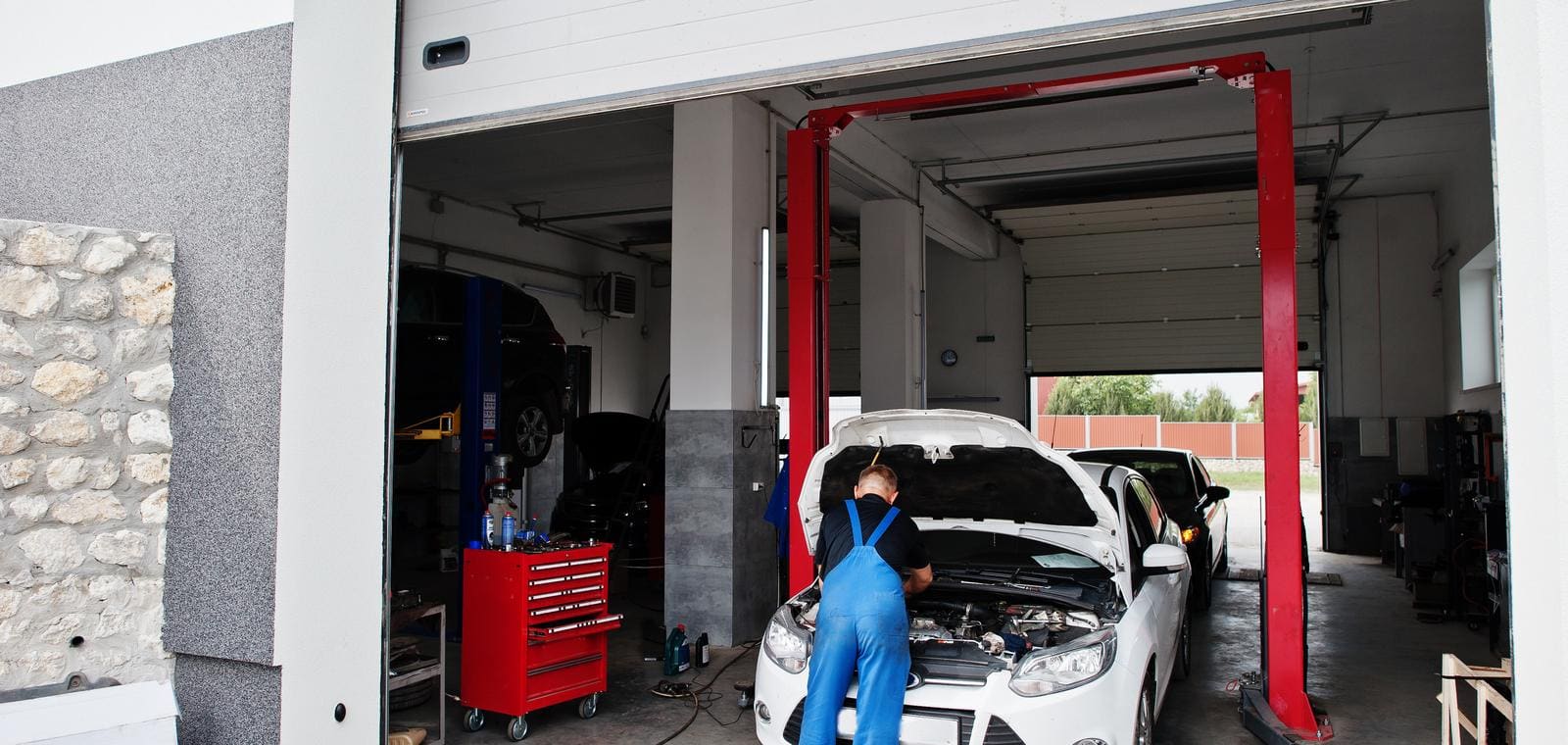 Un mecánico trabaja en el motor de un coche con el capó abierto en un taller