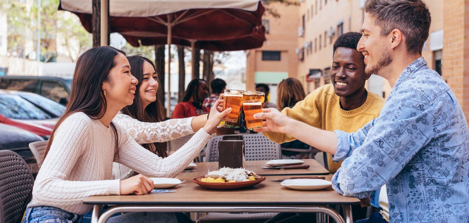 Cuatro amigos brindan con cañas en la terraza de un restaurante de calle