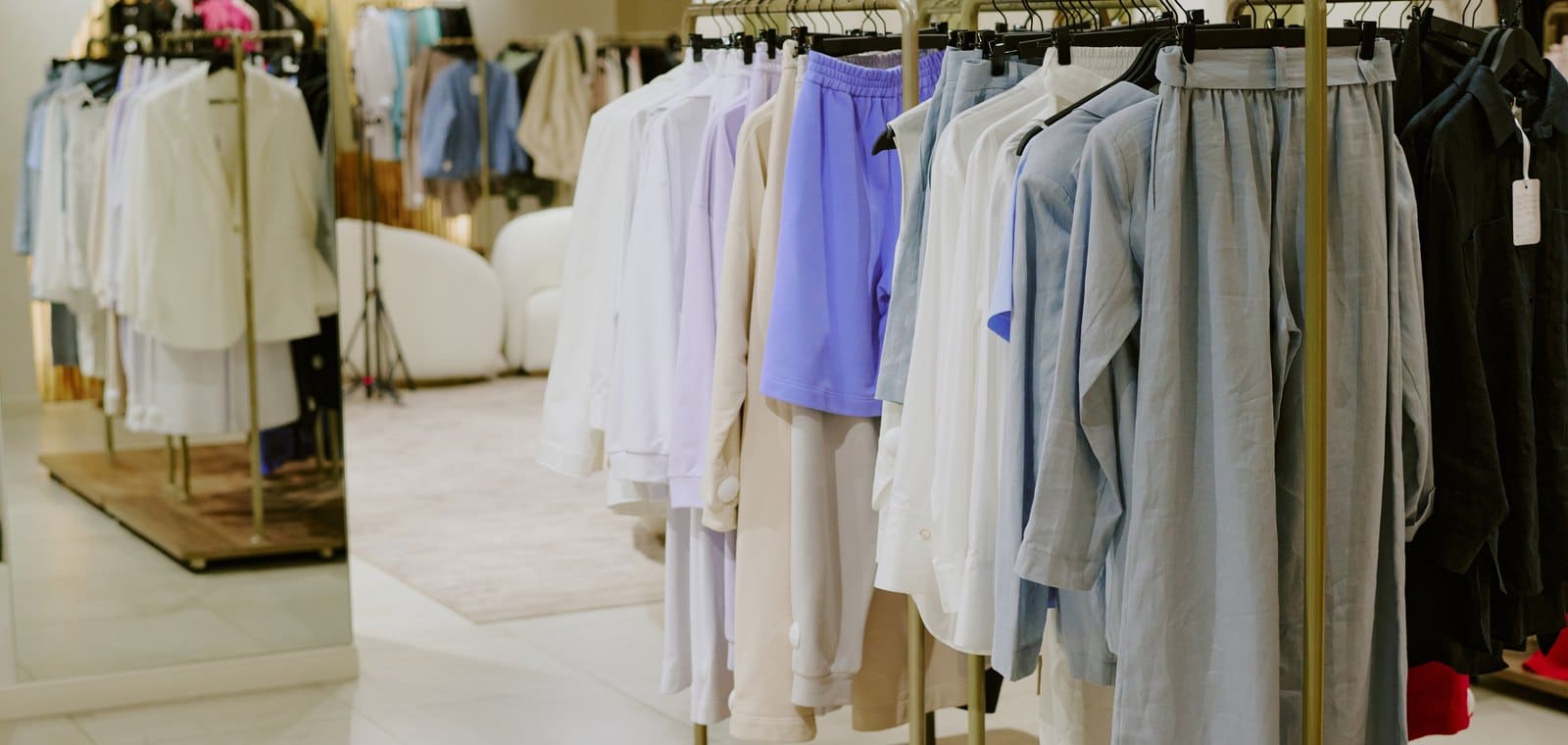 Percheros con ropa colgada en el interior luminoso de una tienda
